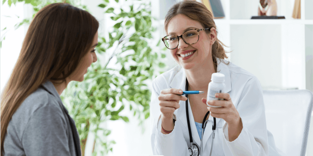 A woman consults a doctor, holding a pill bottle, seeking medical advice and discussing her medication.