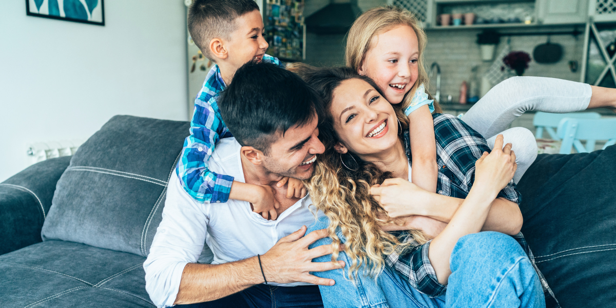 Image of a joyful and healthy family seated on a couch with two kids.