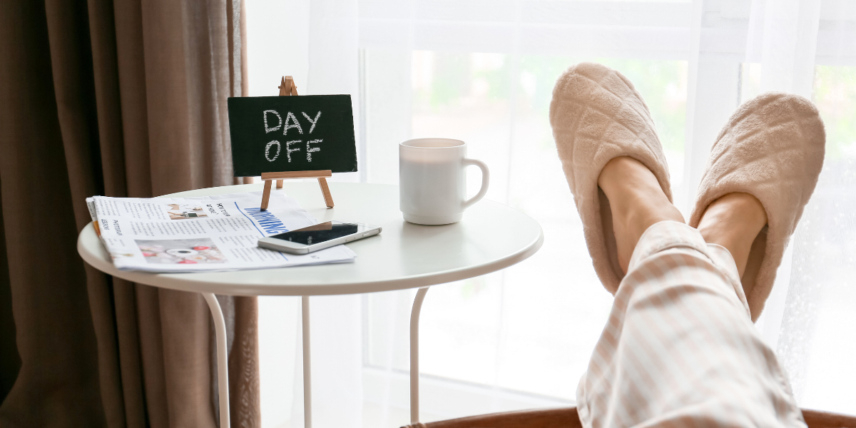 Person's feet on table with coffee cup and day off sign.