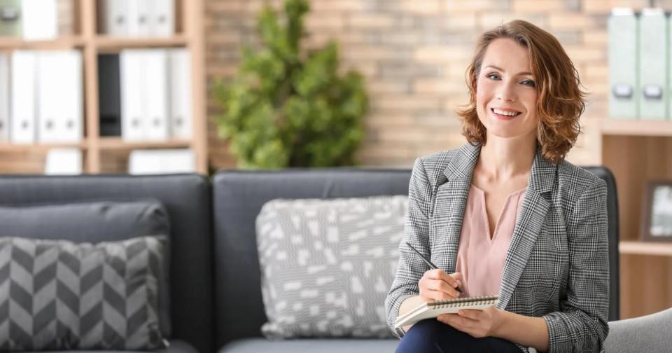 Female psychologist on a couch, with a notebook in hand.