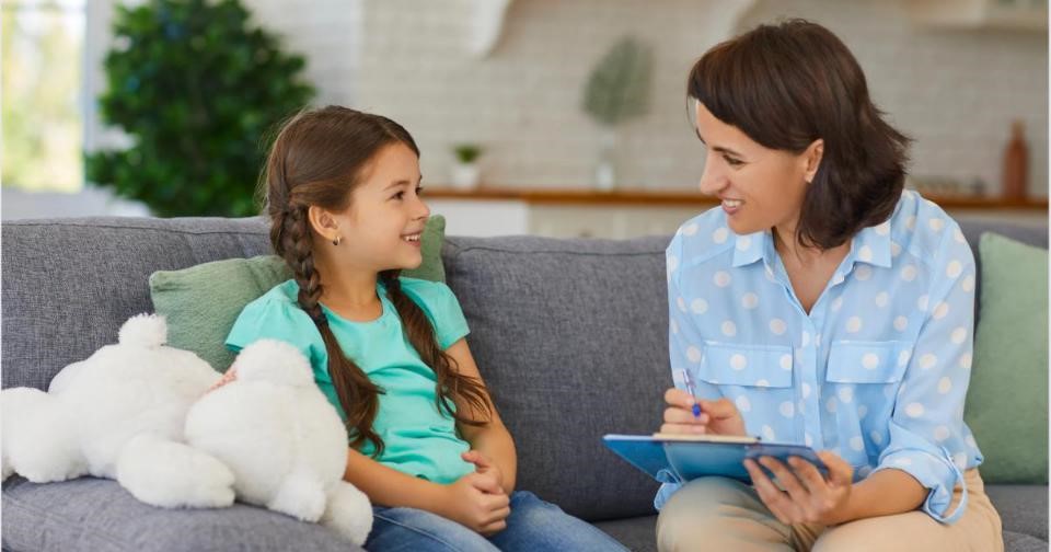 Psychologist and girl engage in a therapy on couch, psychologist listens attentively.