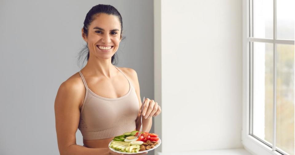 A woman enjoying a nutritious post-workout meal, holding a plate of healthy food.