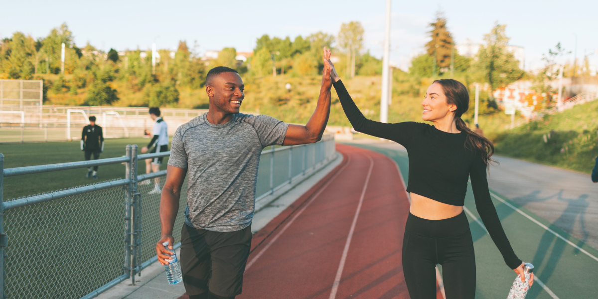 Image of a man and woman happily high-fiving after exercising.
