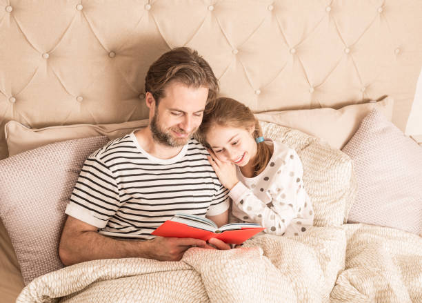 Father and daughter reading a book in a bed