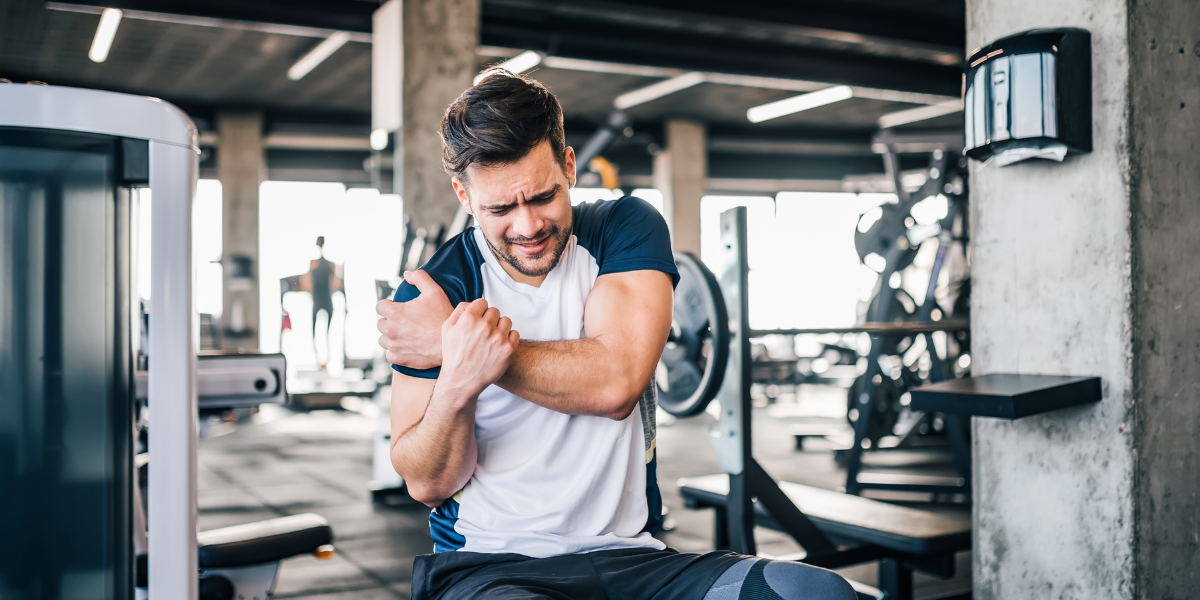An athlete in a gym grimacing in pain due to an injury.